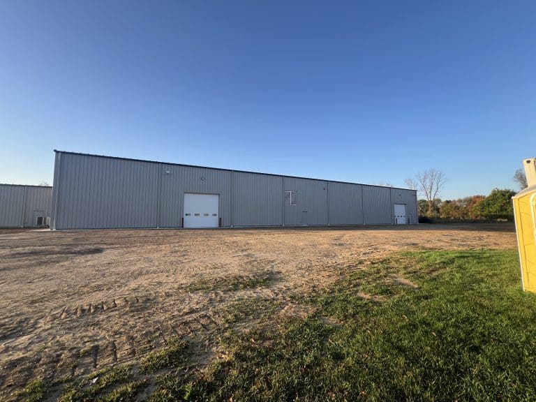 Completed 50 by 160 foot pre-engineered metal building addition in Marcellus, Michigan, with overhead doors and a graded lot.